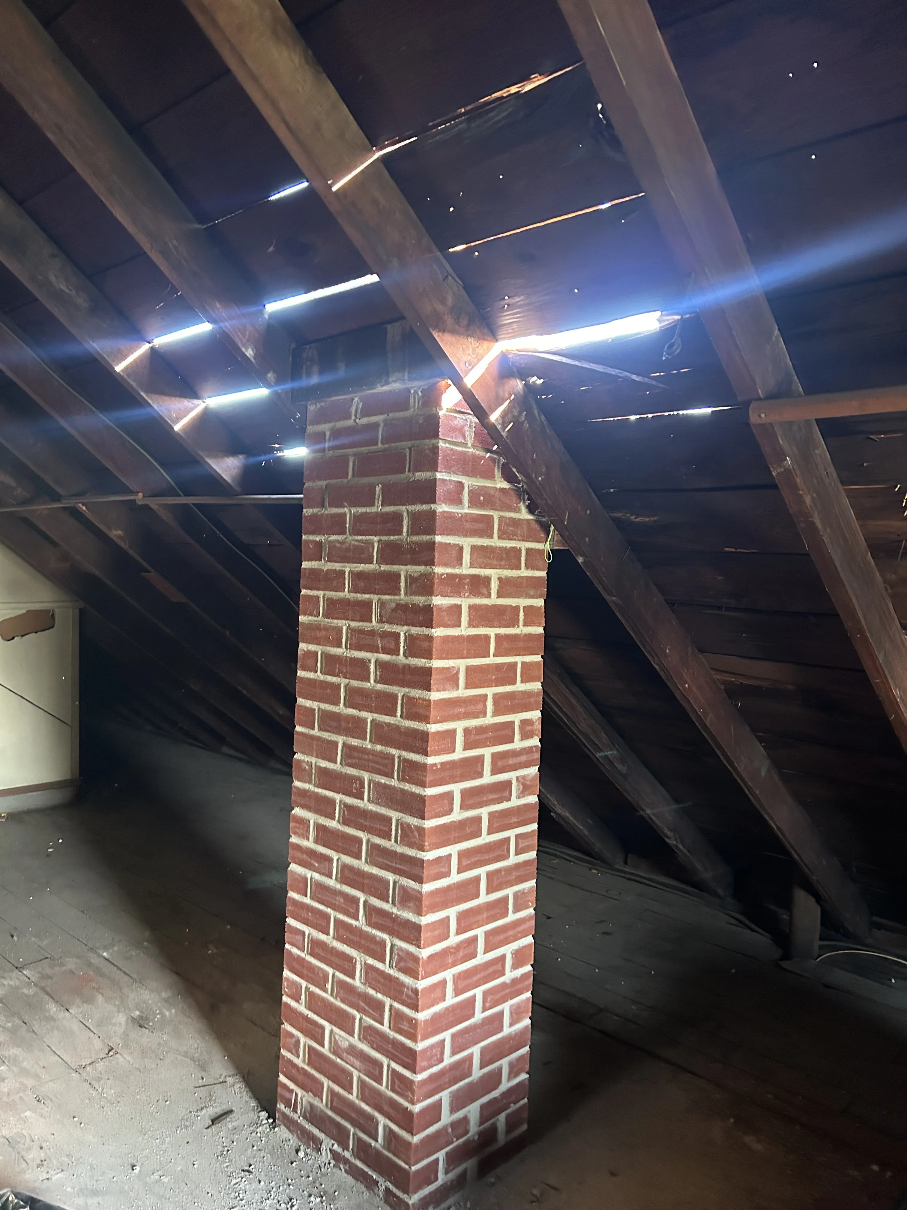 Finished brick chimney passing up through the attic rafters, fully rebuilt with clean brickwork.