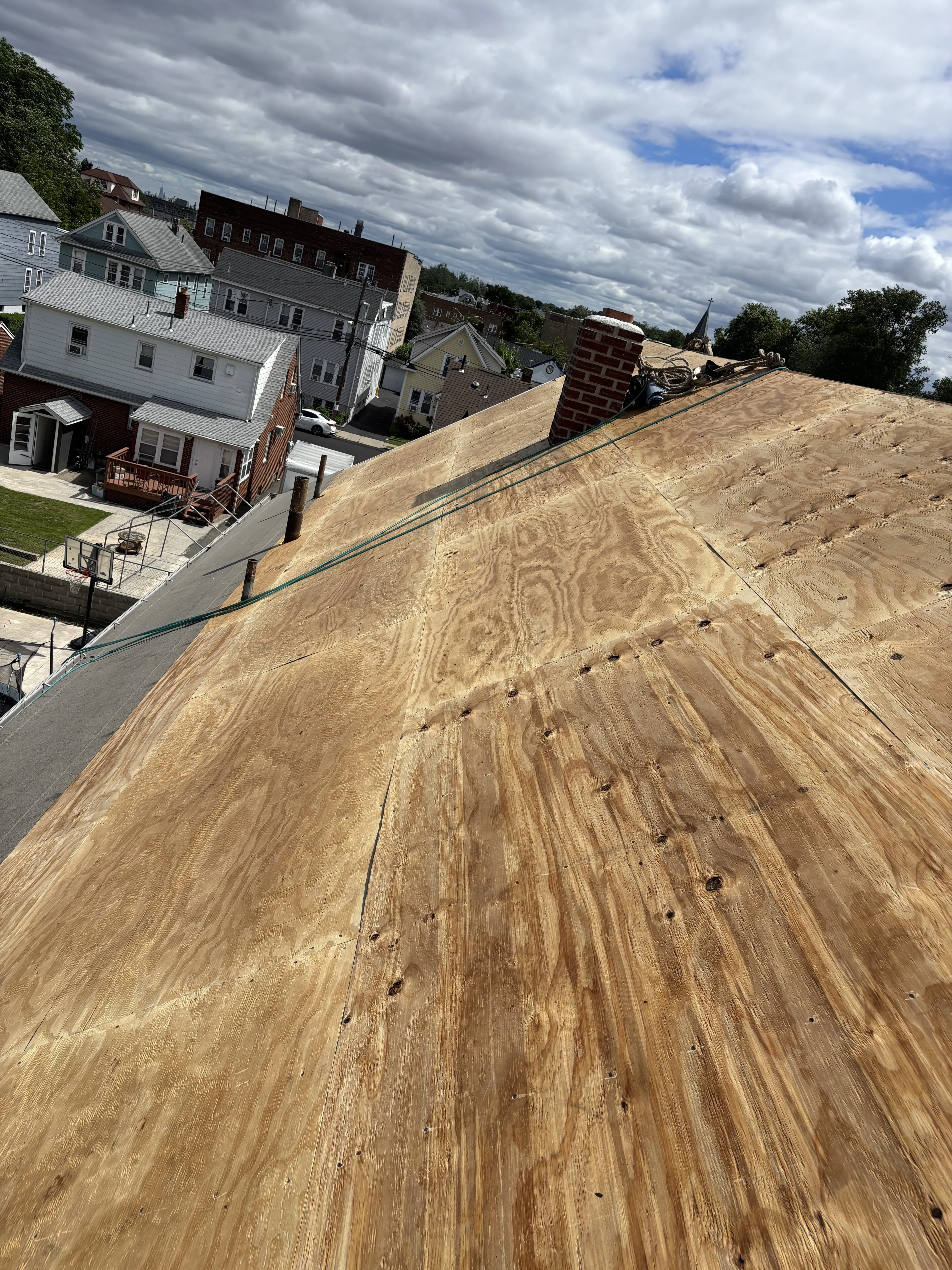 Fresh plywood sheathing laid over the entire roof, fastened and ready for underlayment.