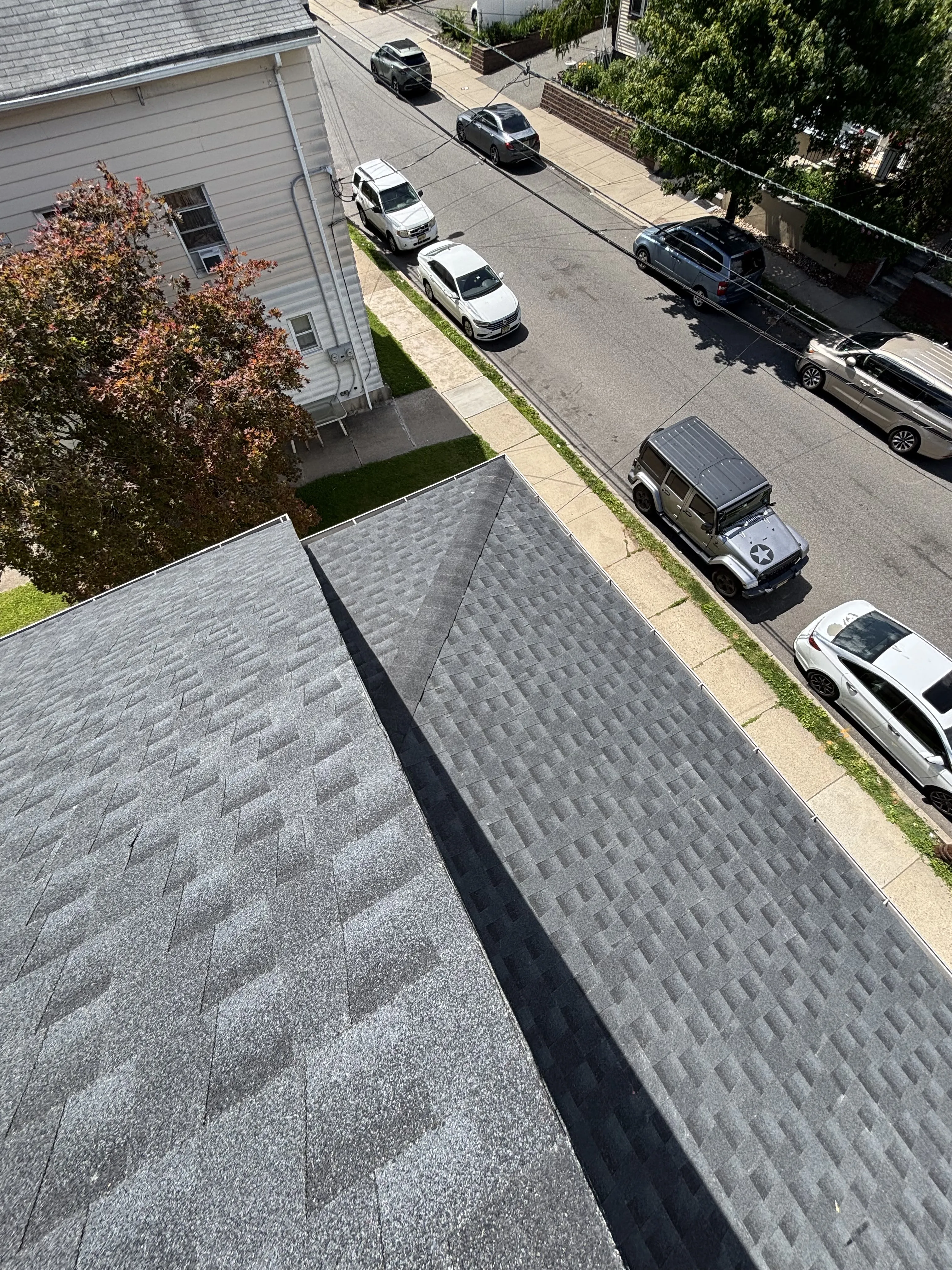 Completed GAF HDZ Charcoal shingle roof from the same elevated vantage, looking down the finished slope toward the street.