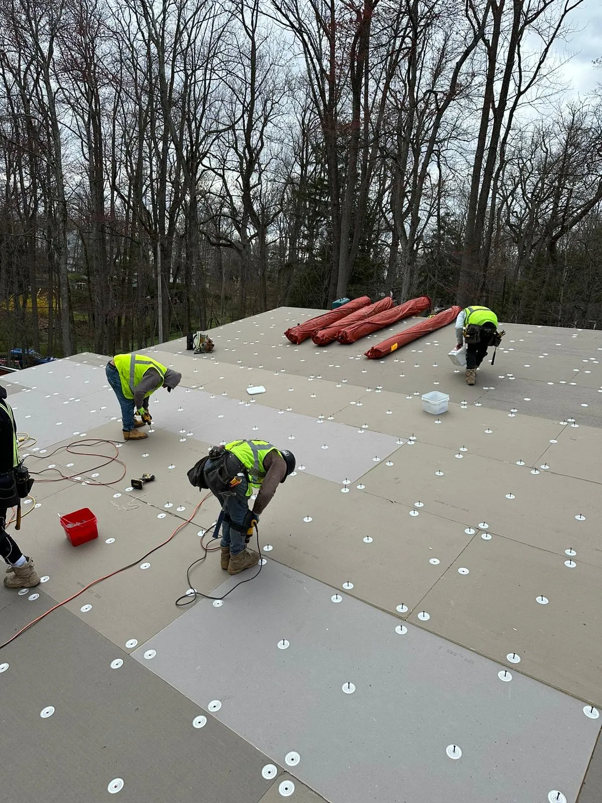 Roof insulation boards laid edge to edge and held by fastener plates across the new deck.