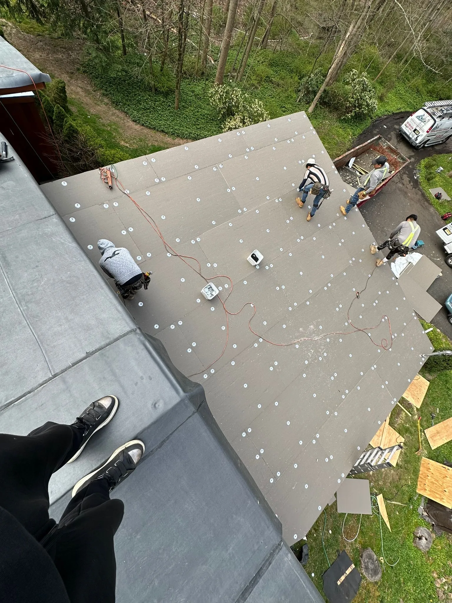 Insulation boards and fastener plates covering the large flat roof, seen from above with a work van below.